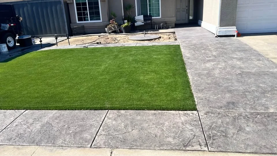 Finished concrete border with new green sod and landscape rock