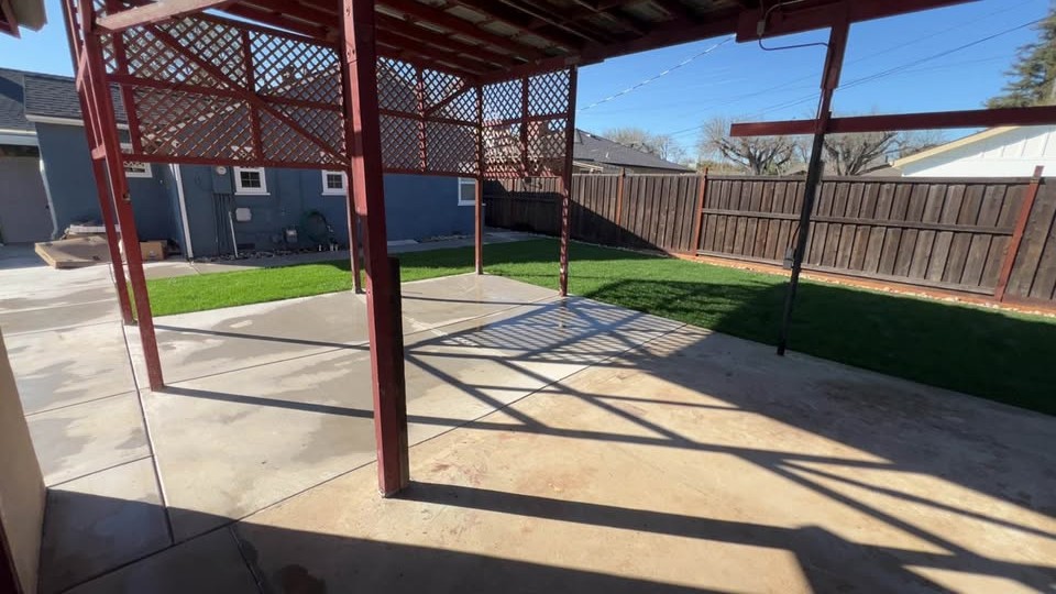 Finished concrete patio beneath a red metal patio cover